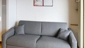 Un canapé gris avec deux coussins, dans une pièce aux murs blancs.