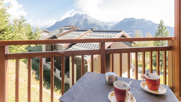 A balcony with a table, two cups, and a view of mountains. - Renovated 2-room apartment, 6 people, southwest balcony, La Rosière (La Rosière)
