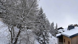A snow-covered landscape with a building featuring a sloped roof and wooden siding. - Renovated 2-room apartment, 6 people, southwest balcony, La Rosière (La Rosière)