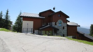 A two-story lodge with a stone facade and a metal roof, surrounded by trees and a clear sky. - Renovated 2-room apartment, 6 people, southwest balcony, La Rosière (La Rosière)