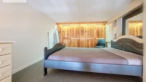 A bedroom with a bed, a dresser, a chair, and wooden paneling on the walls. - Renovated bright studio, balcony, near slopes, parking included (La Rosière)