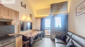 A modern kitchen with a dining area and a leather sofa. - Renovated bright studio, balcony, near slopes, parking included (La Rosière)