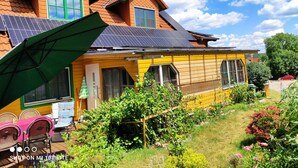 A house with a sloped roof, solar panels, and a garden with various plants and flowers.