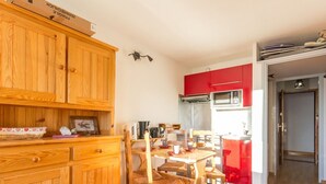 Une cuisine de taille réduite avec des meubles en bois, une table à manger avec des chaises et un appareil électroménager rouge.