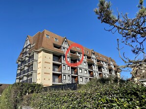 A multi-story building with a traditional architectural style, featuring a mix of brick and white stone facades, multiple balconies, and a clear blue sky in the background. - Cabourg - the beach at your feet (Cabourg)