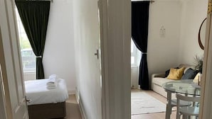 A room with a bed, a sofa, a glass table, and a chair. - Lovely 1-bed Apartment in London - View of Shard (London)