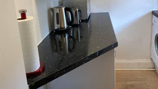 A kitchen counter with a coffee maker, a kettle, and a paper towel holder. - Lovely 1-bed Apartment in London - View of Shard (London)