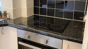A kitchen with a black induction cooktop, a built-in oven, and white cabinetry. - Lovely 1-bed Apartment in London - View of Shard (London)