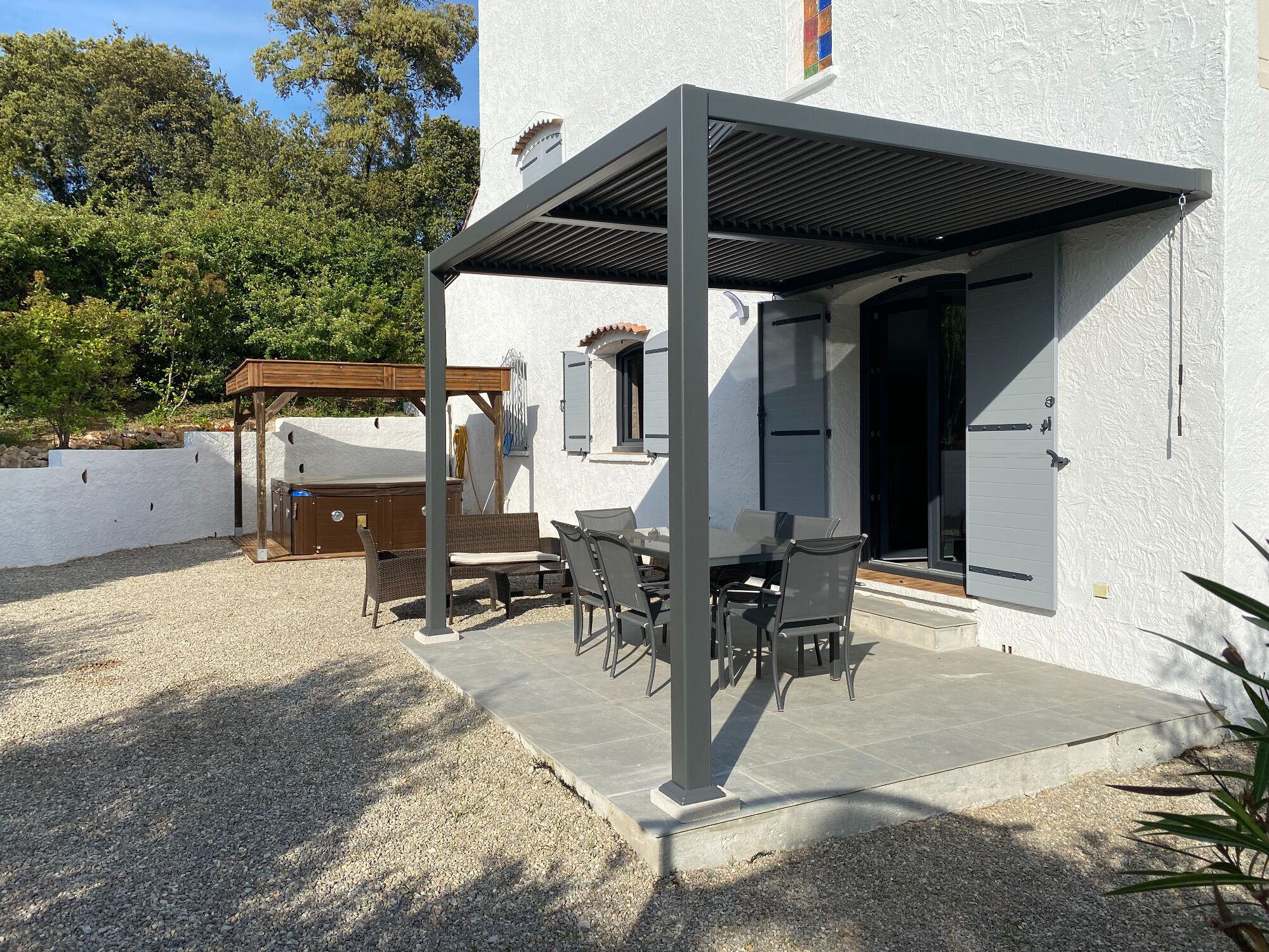 An outdoor patio with a pergola, a barbecue area, and a seating arrangement.