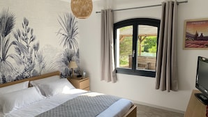 Een slaapkamer met een bed, nachtkastje, lamp, raam met gordijnen, wanddecoratie van planten, en een televisie.