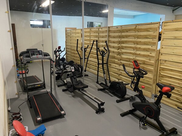 Un gimnasio con diferentes equipos de ejercicio, incluyendo cintas de correr, elípticas y máquinas de pesas.