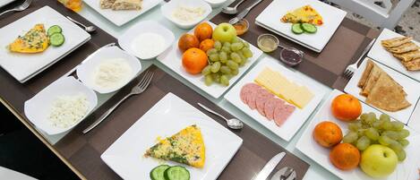 A table set with various breakfast items including eggs, fruits, and cheese.