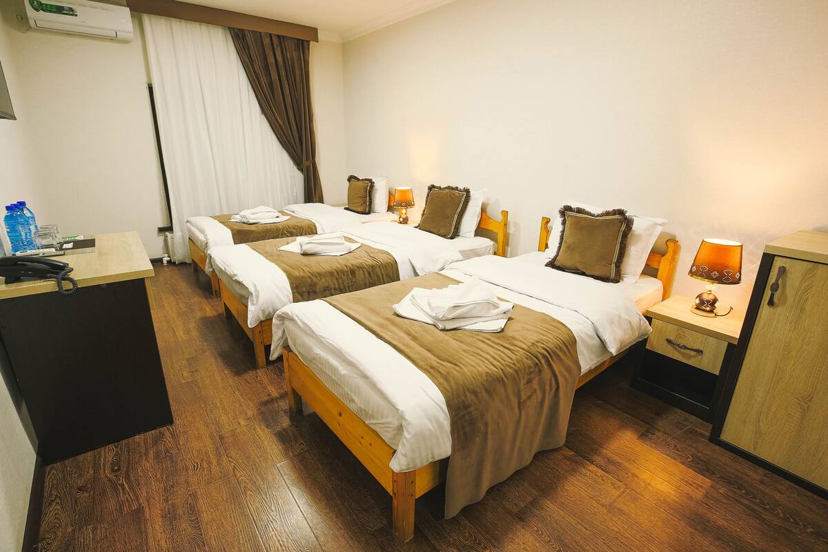 A hotel room with three beds, a desk, and a wardrobe.