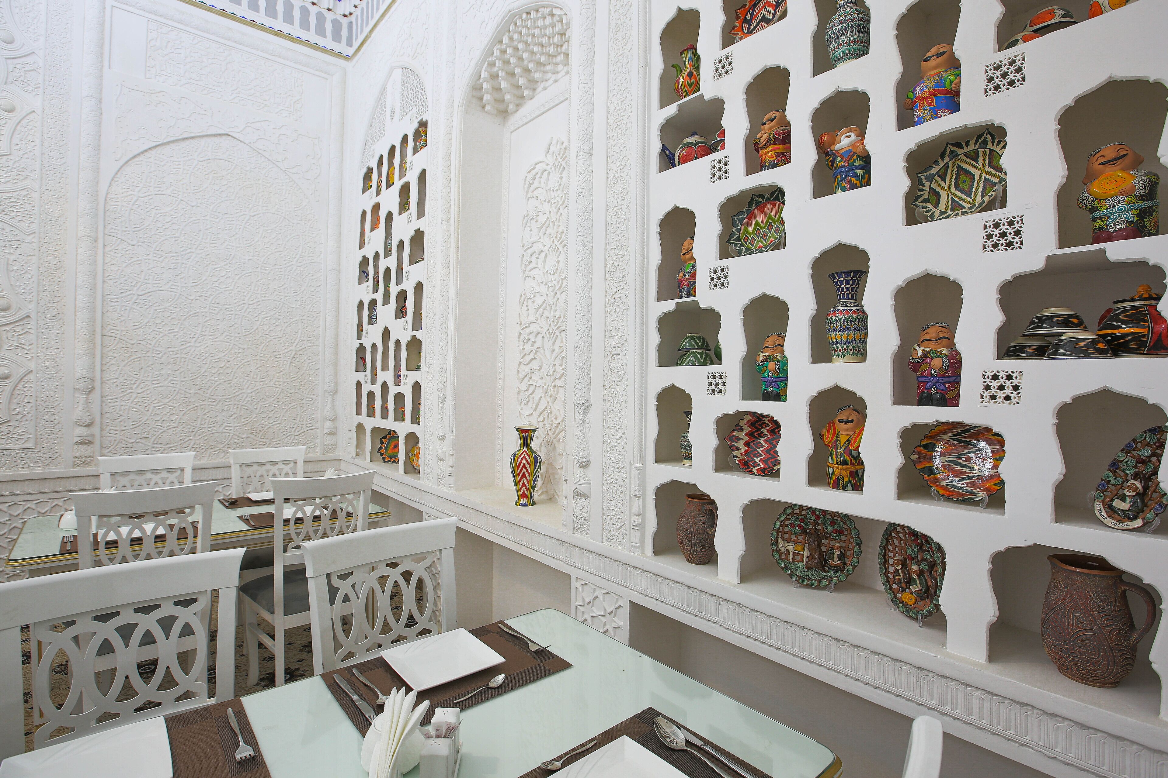 A dining area with white ornate walls, multiple tables, and chairs.
