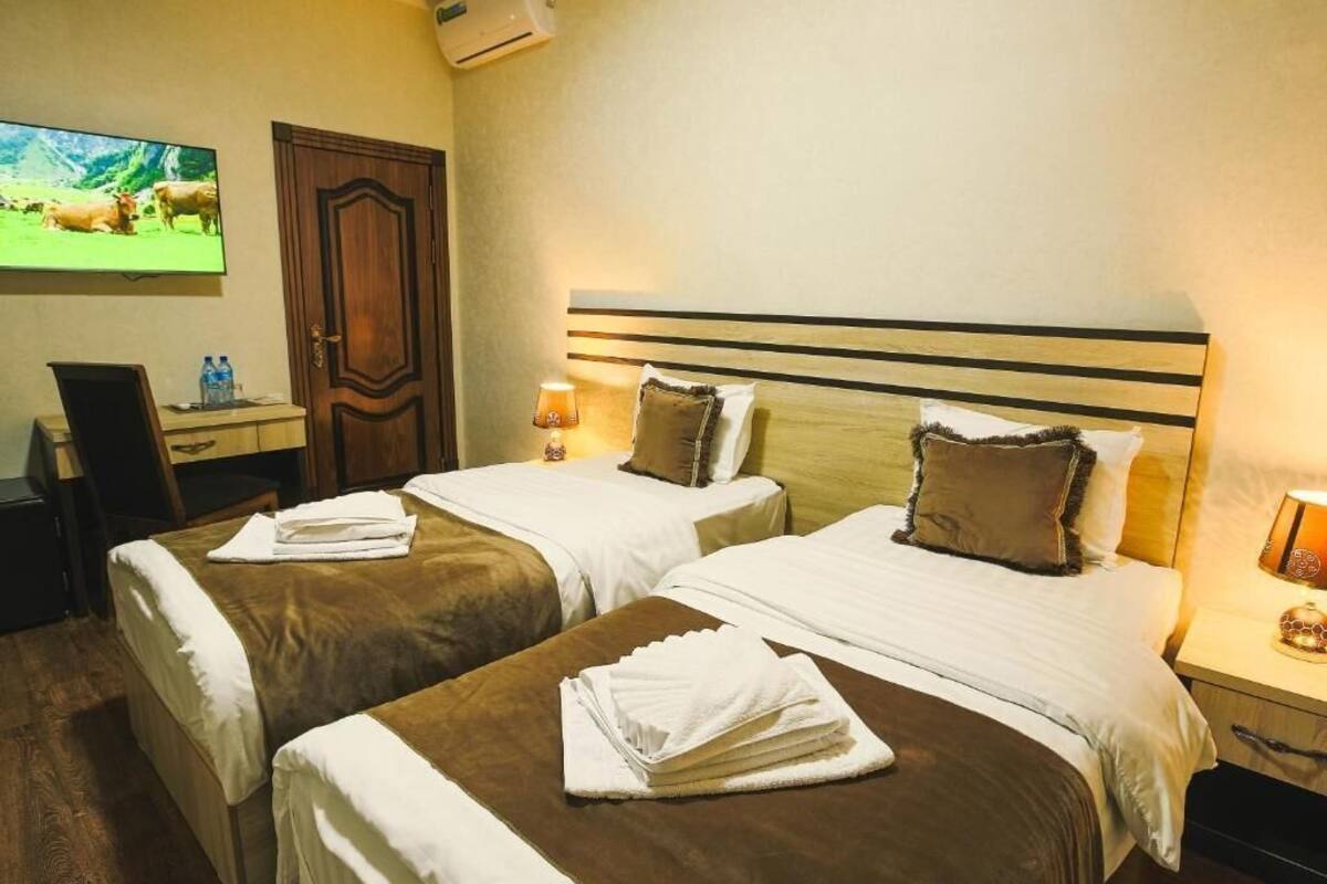 A hotel room with two beds, a TV, a desk, and a door.