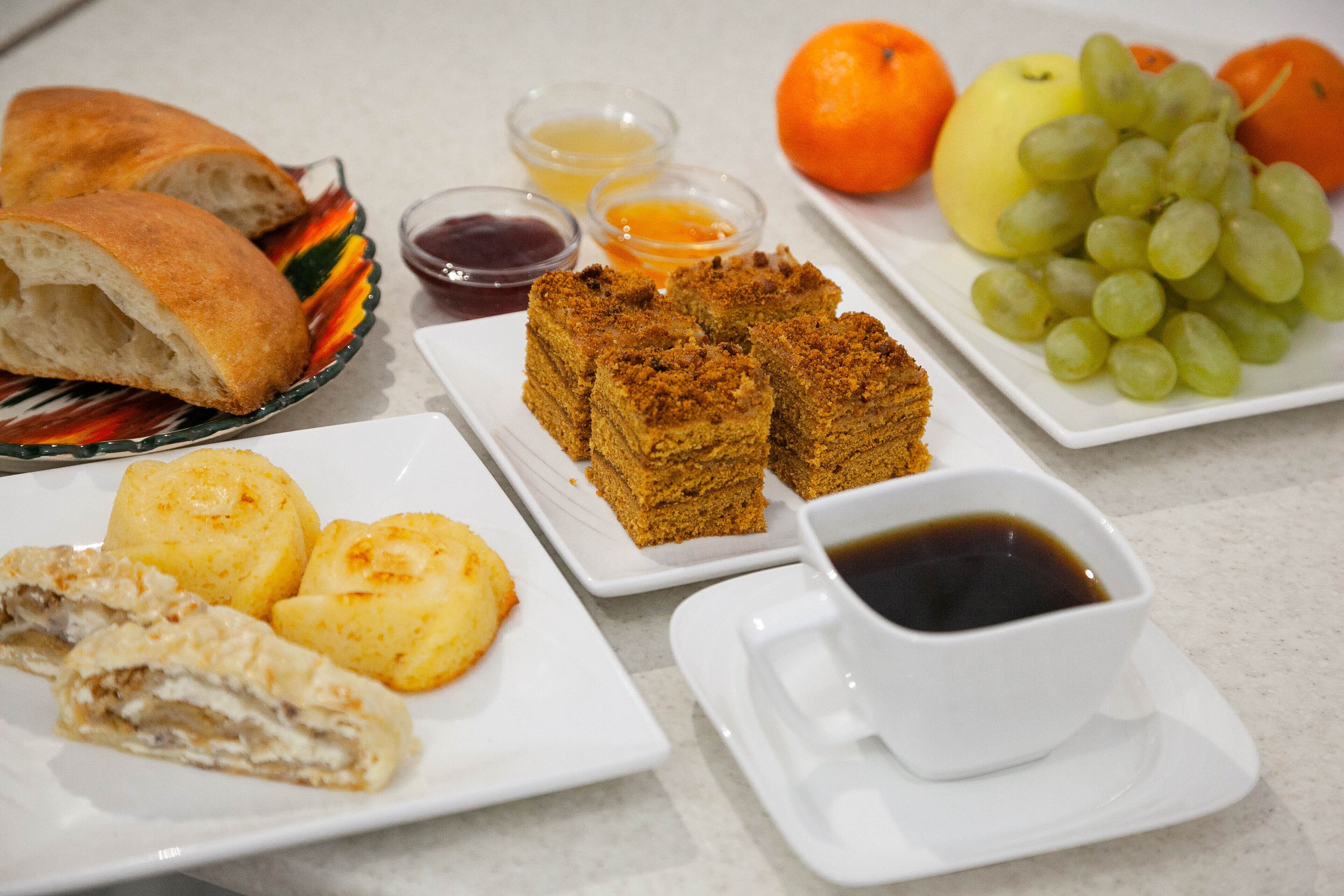 A table with bread, pastries, fruit, and condiments.