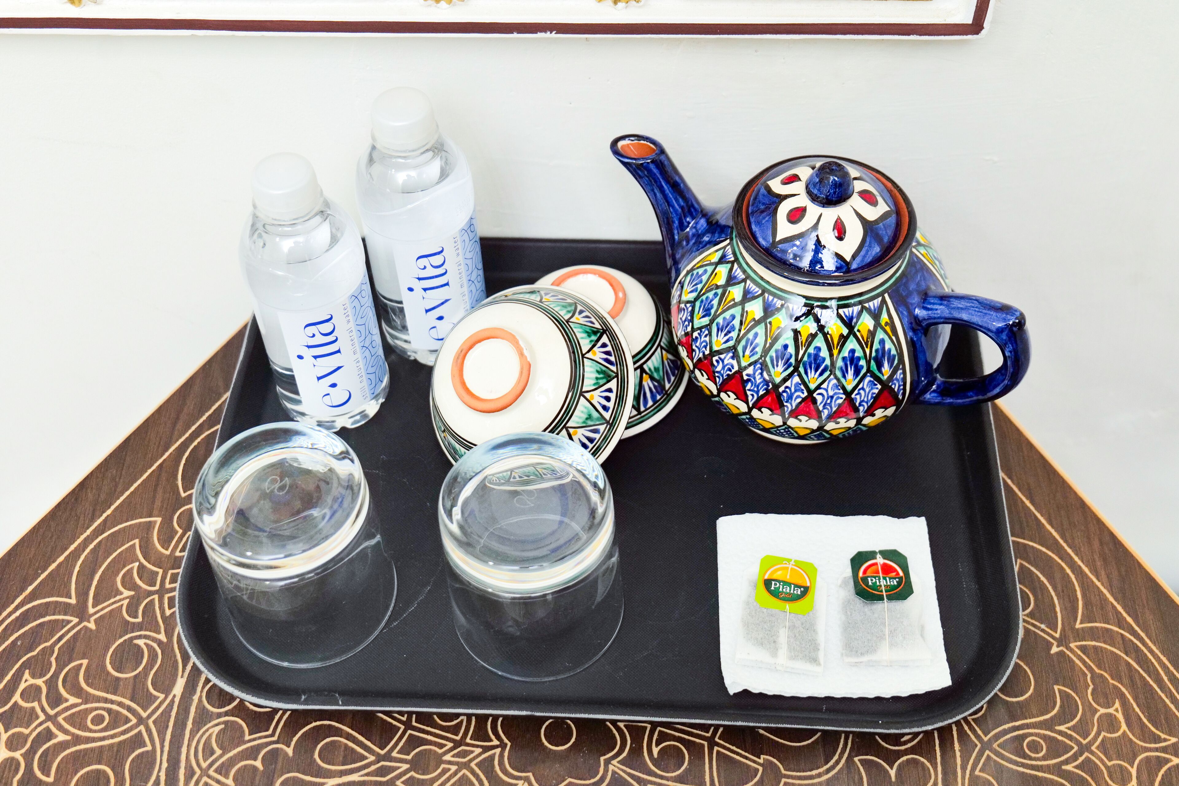 A tray with two water bottles, two glasses, a teapot, and two tea bags.