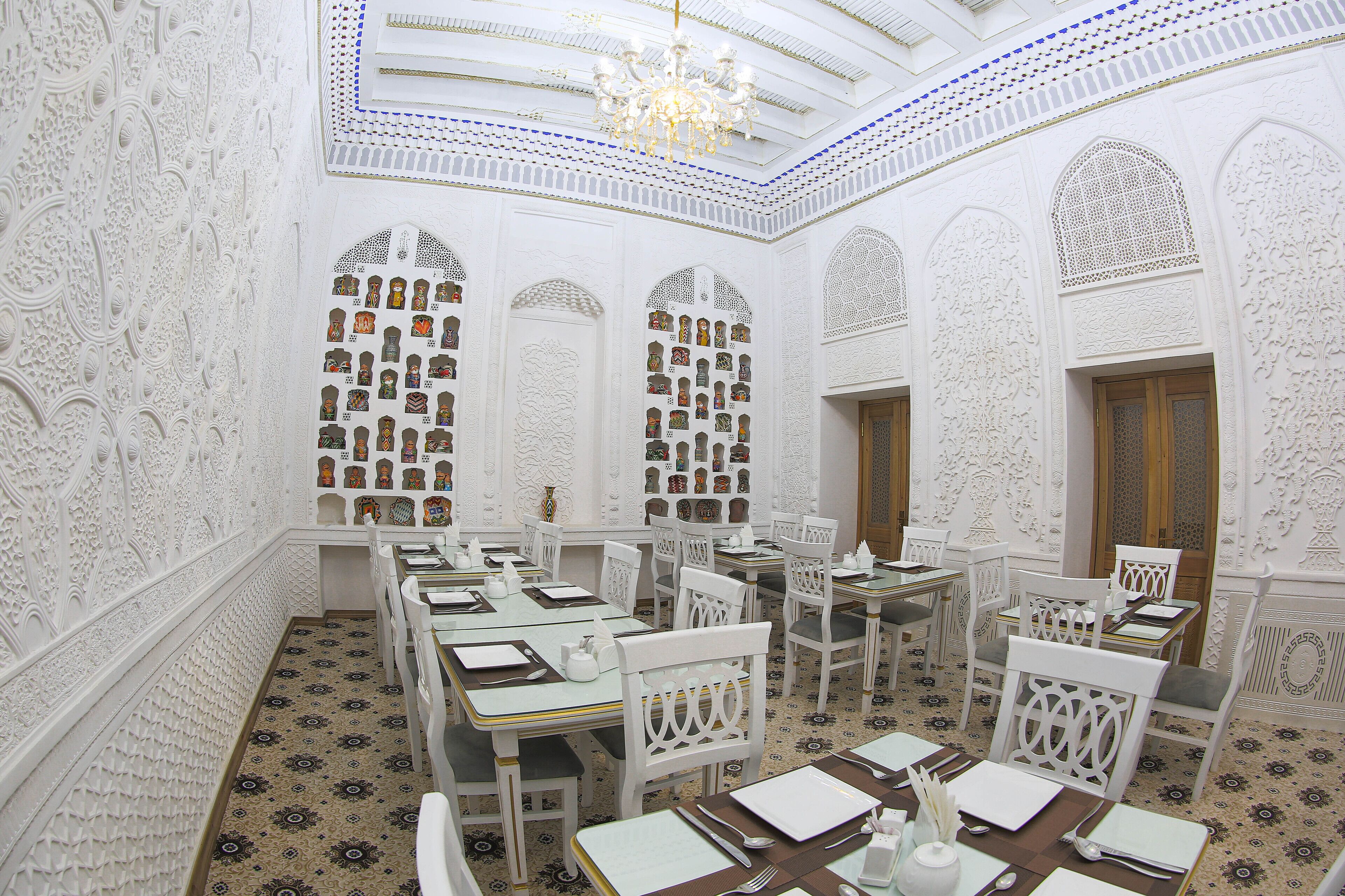 A dining area with ornate white walls, intricate ceiling design, and patterned floor tiles.