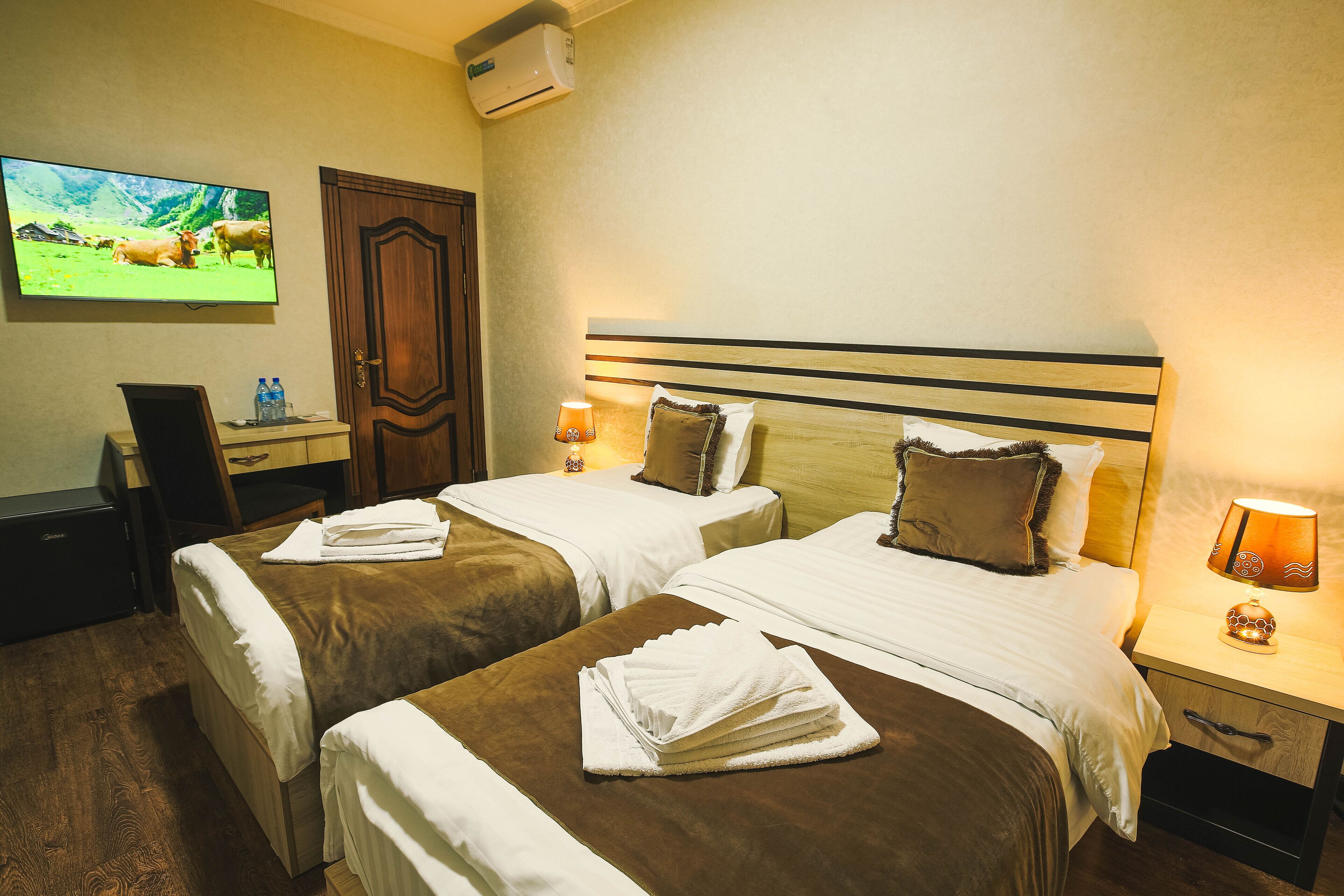 A hotel room with two beds, a TV, a desk, and a chair.
