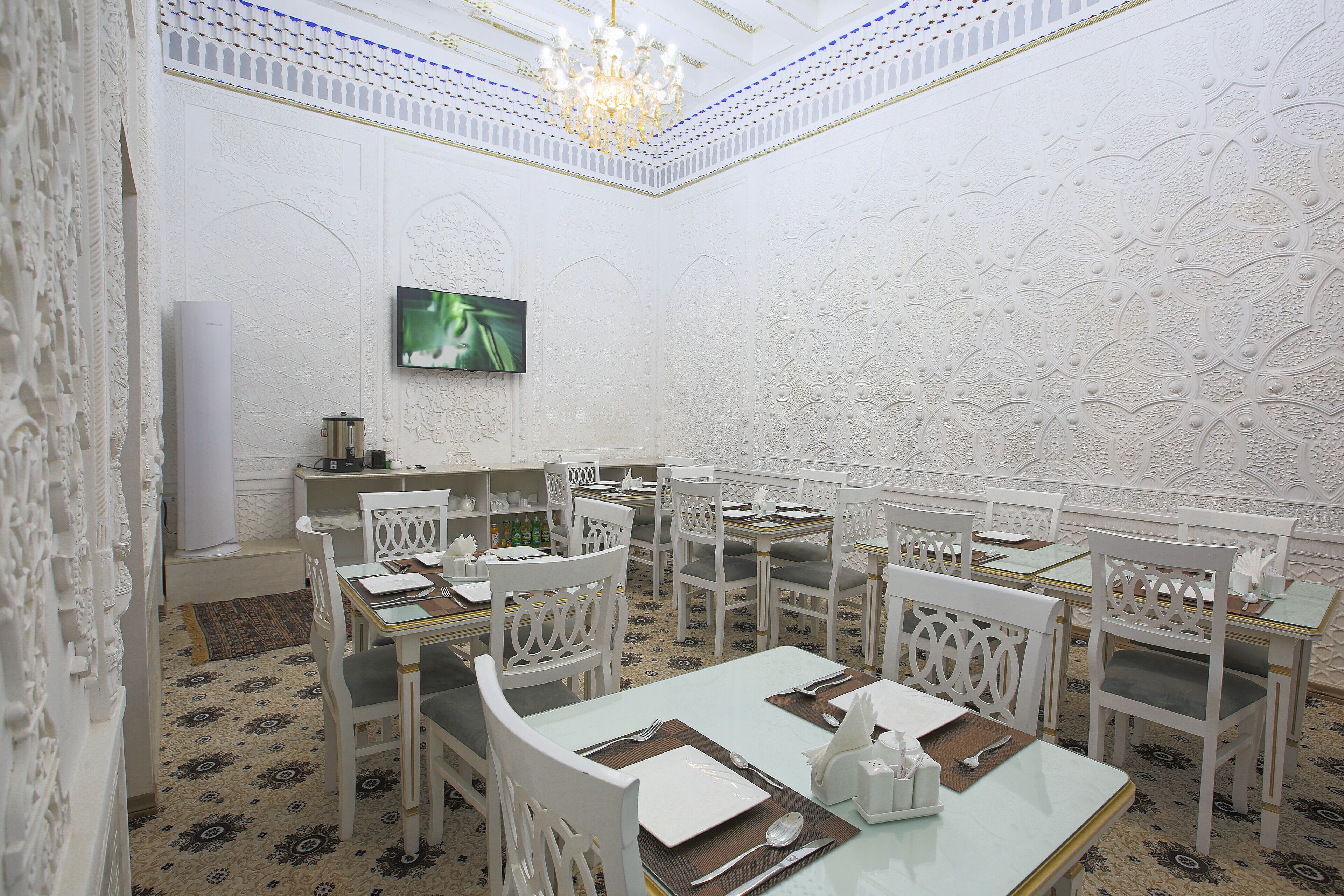 Un comedor con mobiliario blanco, una araña y baldosas de suelo estampadas.