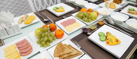 Una mesa dispuesta con diferentes alimentos para el desayuno, como huevos, jamón, queso, tostadas y frutas.