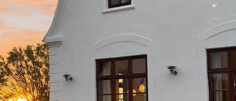 A white building with multiple windows, a white picket fence, and a stone wall.