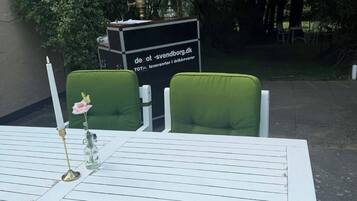 Una mesa blanca con sillas verdes, una vela y un florero con una flor.