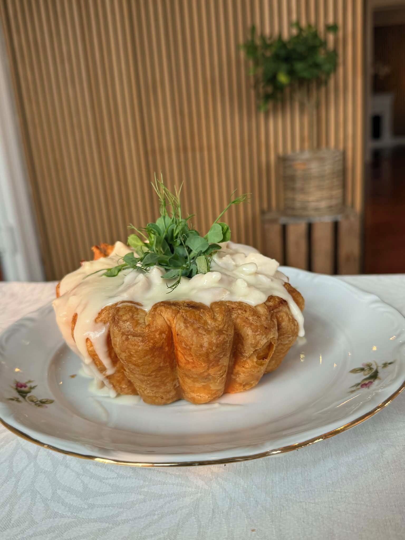 Un postre en un plato con un borde decorativo, sobre un mantel.