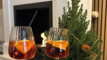 Two glasses of amber-colored beverage on a wooden table with a Christmas tree in the background.