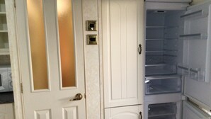 A kitchen with white cabinets, a microwave, and a refrigerator. - Beautiful 2-bed Holiday Home nr Kynance Cove (Helston)
