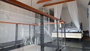 A room with a glass partition, a bed with white bedding, and a canopy.