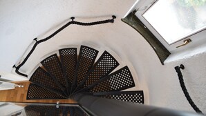 A spiral staircase with a black railing and a window at the top.