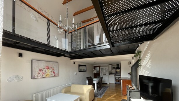 A spacious living area with a high ceiling, a chandelier, a fireplace, and a television.