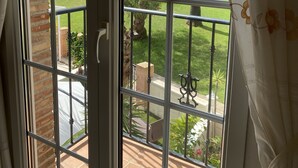 A view through a window with a metal grid, a brick wall, and a pool in the background. - Costa Blanca Los Dolses, Spanish cozy apartment, solarium garden pool beach golf (Los Dolses)