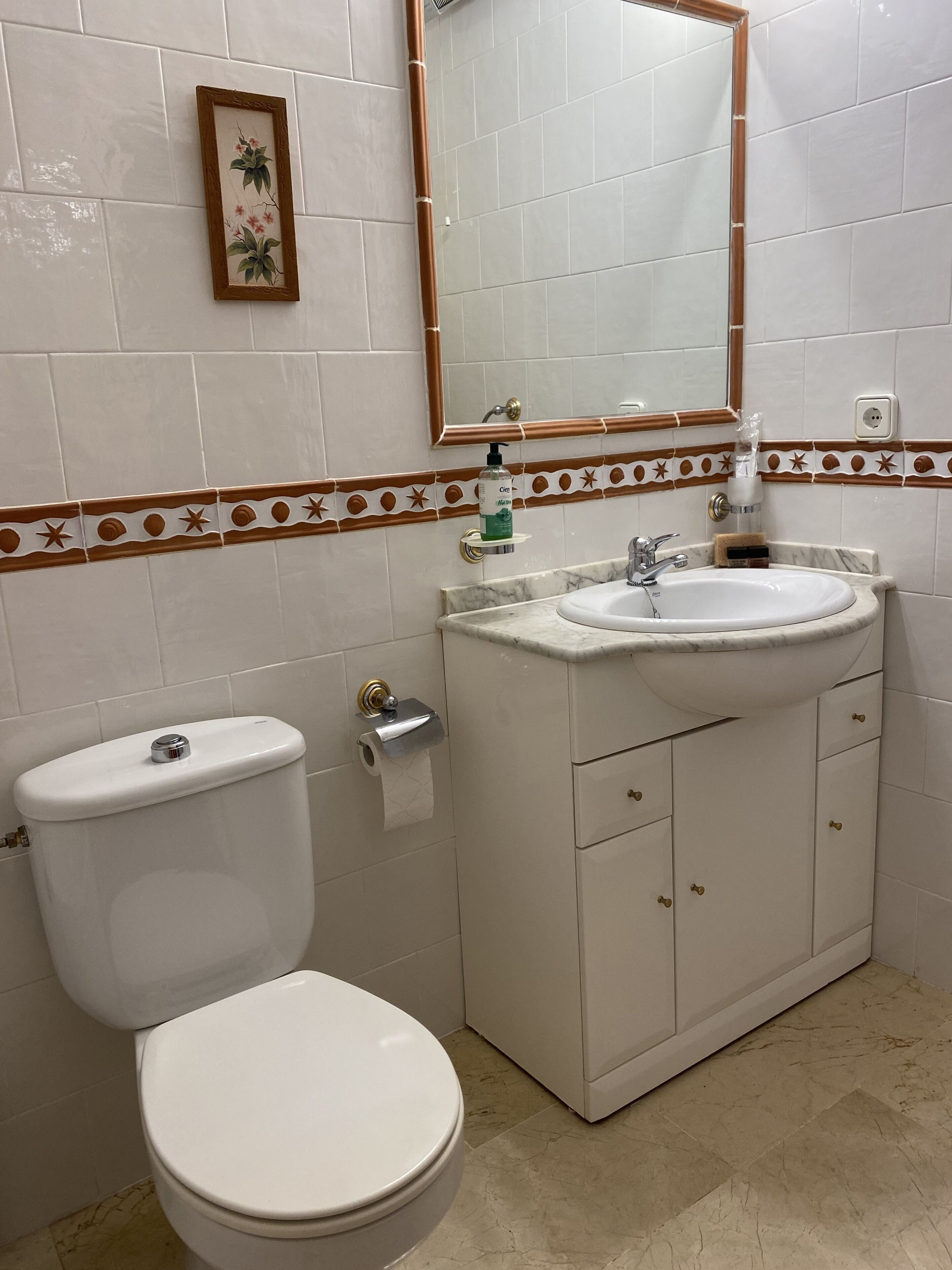 A bathroom with a toilet, sink, and mirror.