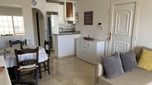 A modern kitchen with white cabinets, a built-in oven, and a dining area with a table set for two. - Costa Blanca Los Dolses, Spanish cozy apartment, solarium garden pool beach golf (Los Dolses)