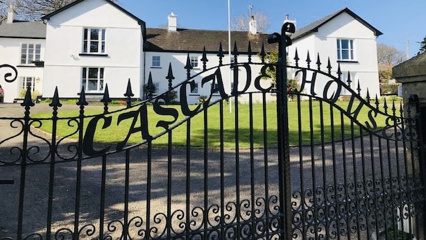 Una entrada con puerta metálica que lleva el nombre "CASCADE HOUSE" en letras grandes.