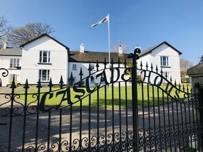 Une entrée fermée par un portail sur lequel est inscrit en grandes lettres le nom « CASCADE HOUSE ».