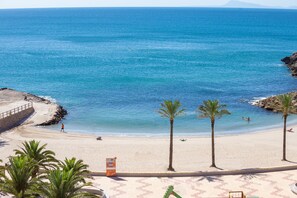 A beach with clear blue water, palm trees, and a lifeguard tower.