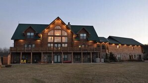 A large log cabin with a prominent central window, multiple balconies, and a spacious front porch. - Gorgeous, remote lodge on 100+ acres, 15 min from downtown Indiana (Indiana)