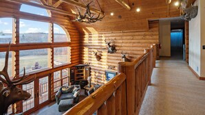 A log cabin interior with a balcony, wooden beams, and deer antlers. - Gorgeous, remote lodge on 100+ acres, 15 min from downtown Indiana (Indiana)