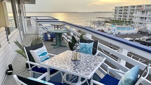 Une terrasse avec des sièges, une table et une vue sur l’eau et les bâtiments.