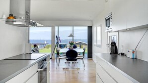 A modern kitchen with a large island, a dining area with a view, and a kitchen counter with appliances. - Beautiful home in Knebel with WiFi (Knebel)