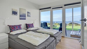 A bedroom with two beds, a large sliding glass door leading to an outdoor area, and artwork on the wall. - Beautiful home in Knebel with WiFi (Knebel)