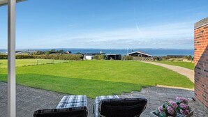 A patio with two chairs, a brick wall, and a view of the sea. - Beautiful home in Knebel with WiFi (Knebel)