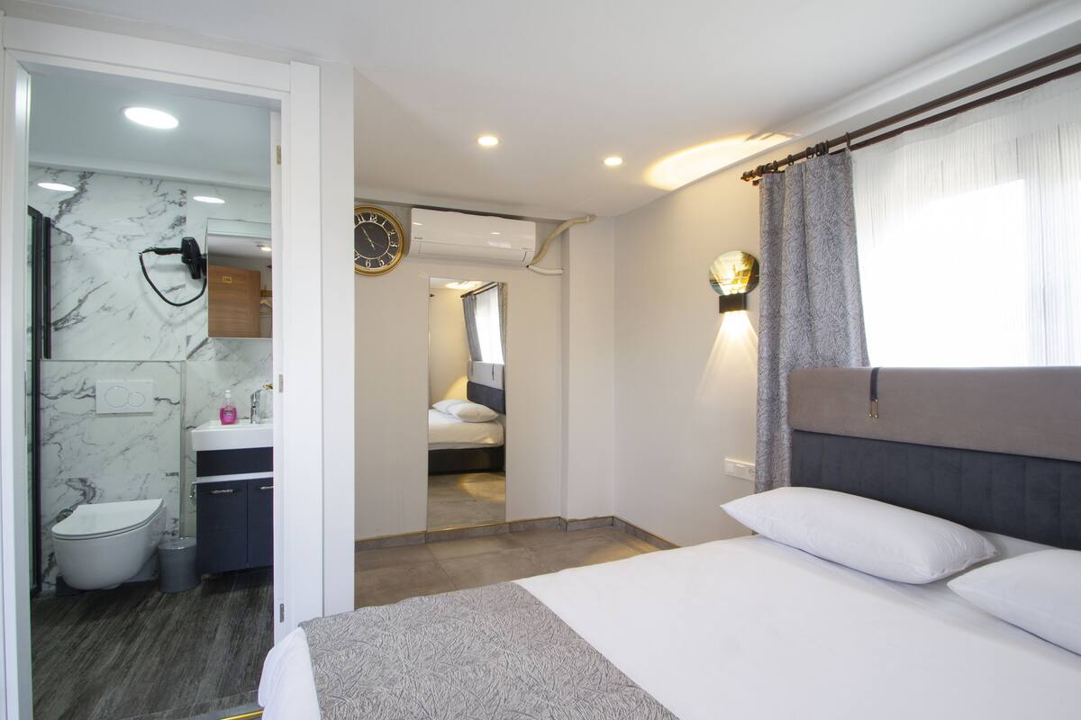 Et hotelværelse med seng, badeværelse og spejl.