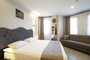 A hotel room with a large bed, a sofa, a wall clock, and a painting. - Turna Hotel (Istanbul)