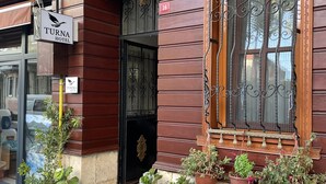 Ingresso di un hotel con facciata in legno, una porta nera e diverse piante in vaso.
