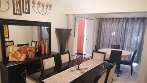 Un comedor con una mesa larga, sillas, un espejo y decoración en la pared.