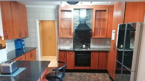 Una cocina con armarios de madera, encimera negra, estufa y refrigerador.